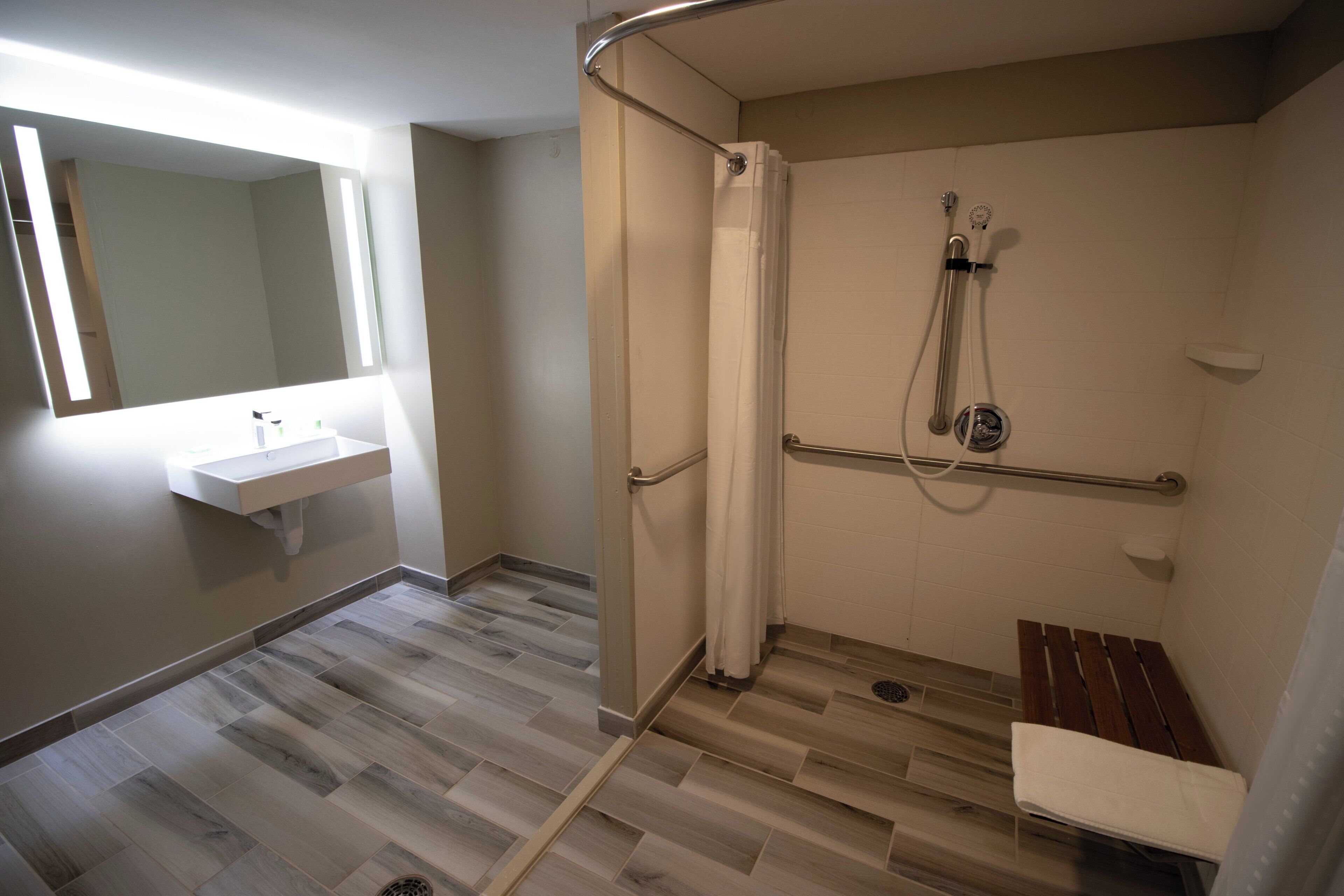 A bathroom with a shower, a sink, and a bench.