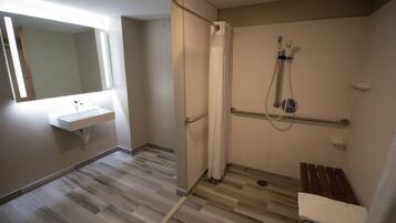 A bathroom with a shower, a sink, and a bench.