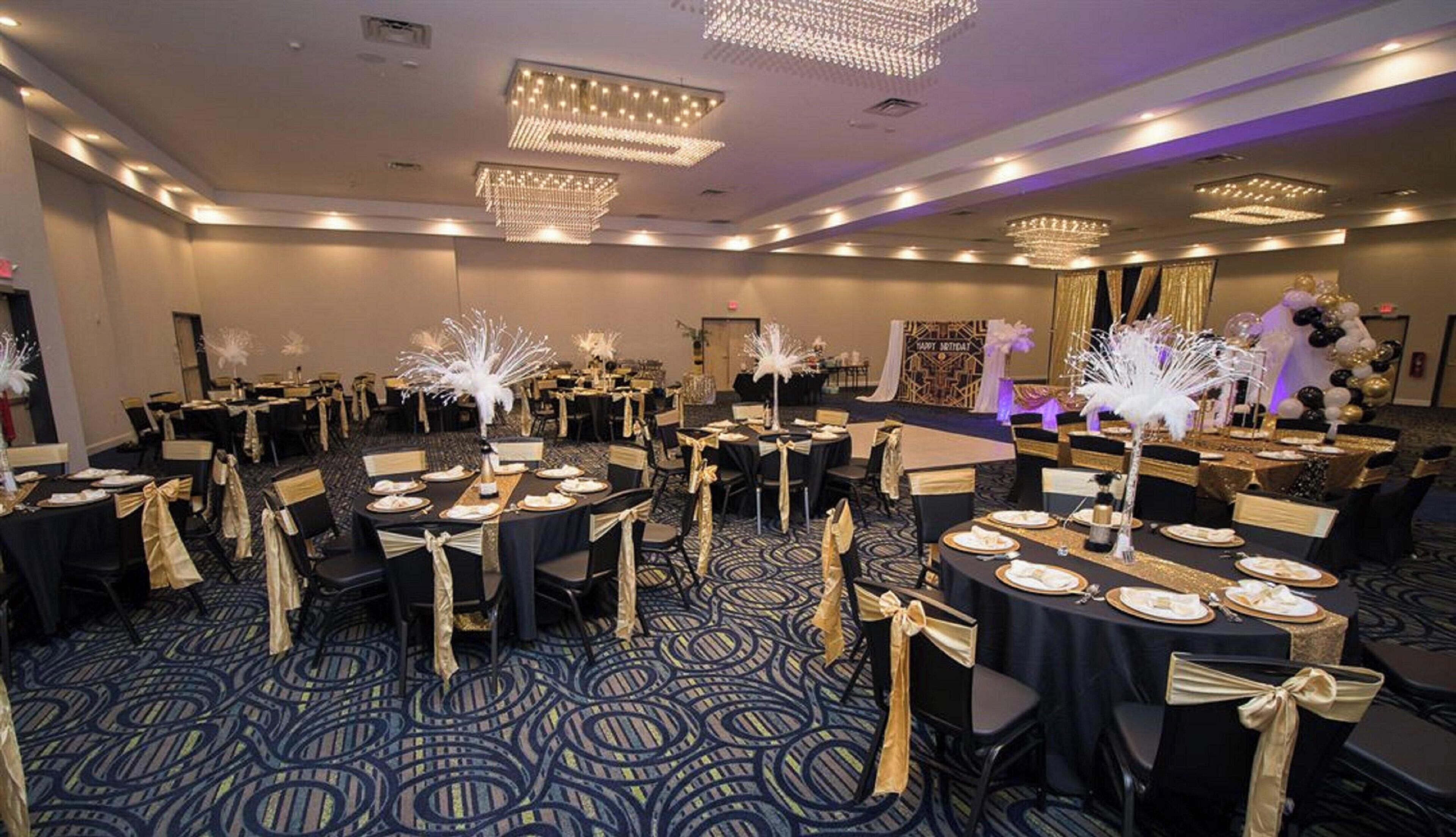 A banquet hall with round tables, chairs, and decorative centerpieces.
