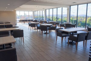 Un comedor amplio con mesas y sillas altas, y ventanas grandes que ofrecen vistas al exterior.
