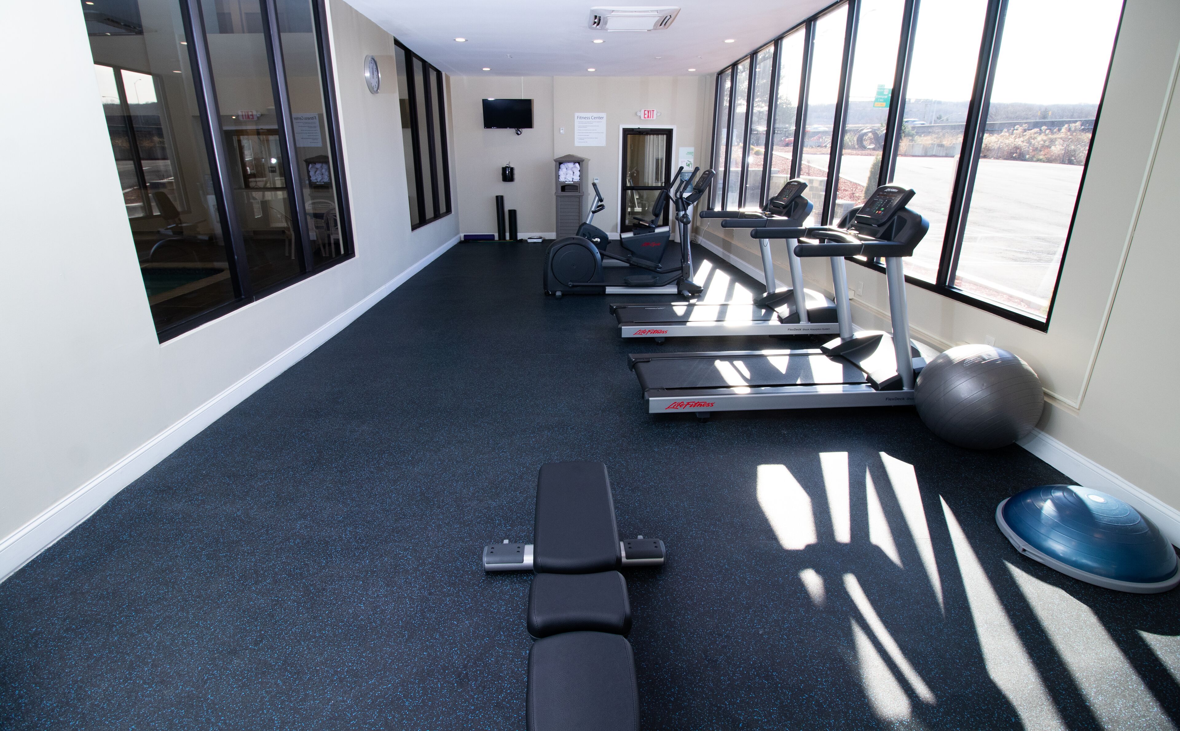 A gym with treadmills, a stationary bike, and an exercise ball.