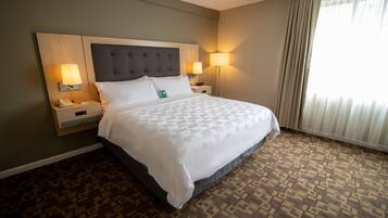 A hotel room with a large bed, two bedside tables with lamps, a telephone, and a patterned carpet.