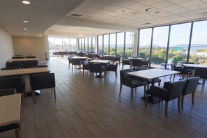 A spacious dining area with large windows offering a view of the outdoors. Tables and chairs are arranged for dining. - Holiday Inn Scranton East - Dunmore by IHG (Scranton)