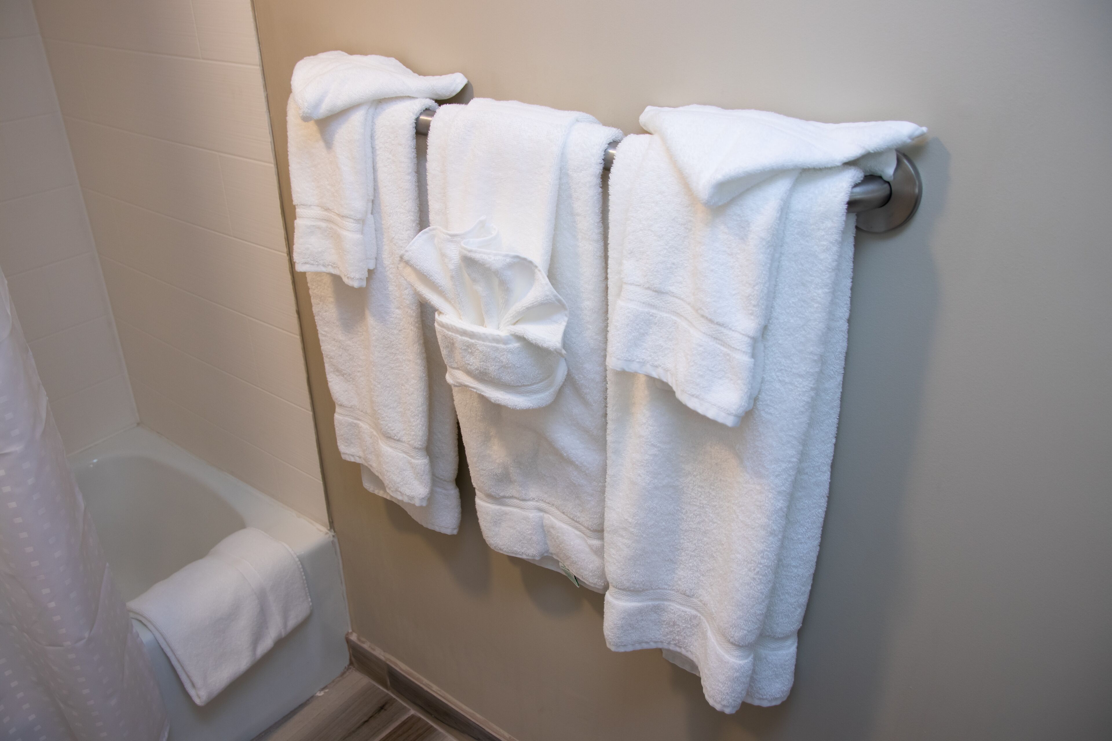 Un baño con toallas blancas colgadas en un toallero metálico.