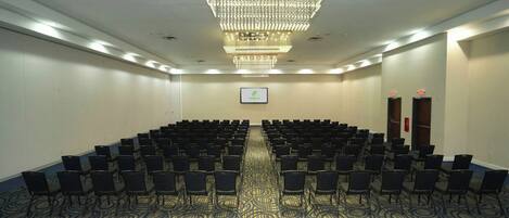 A conference room with rows of chairs, a chandelier, and a Holiday Inn sign on the wall.