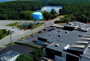 An industrial area with a large blue storage tank, parking lots, and a building with a green sign.