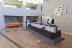 A reception area with a counter, seating, and a wall-mounted sign. - Holiday Inn Scranton East - Dunmore by IHG (Scranton)