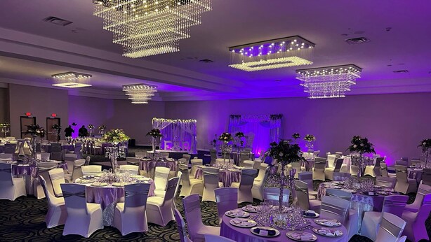 A banquet hall with round tables, white chairs, and chandeliers. - Holiday Inn Scranton East - Dunmore by IHG (Scranton)