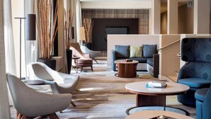 Un moderno vestíbulo de hotel con un sofá, sillones, una mesa de centro y una televisión.