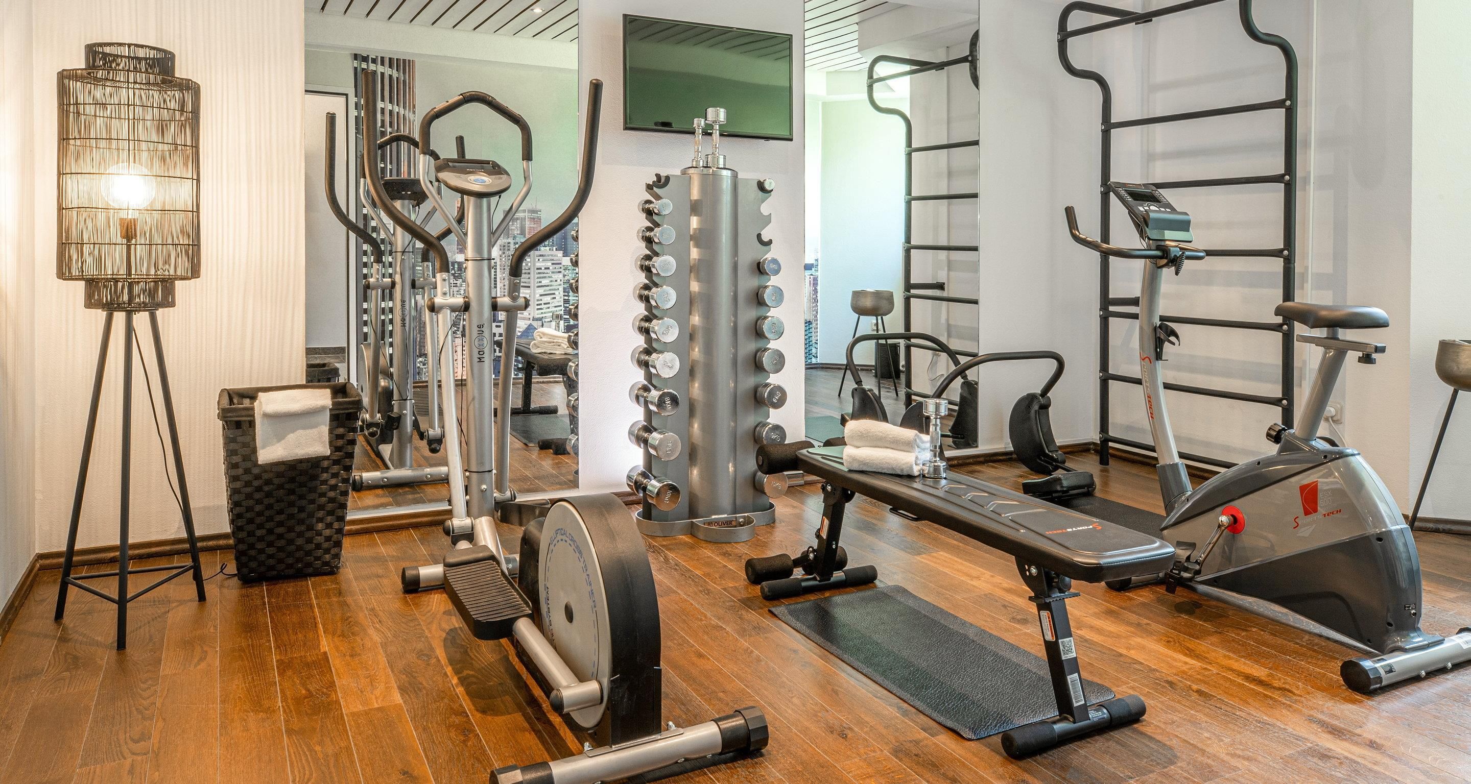 Una palestra con attrezzature cardio, macchinari per pesi e uno specchio.