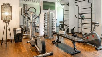 Una palestra con attrezzature cardio, macchinari per pesi e uno specchio.