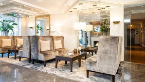 A modern lobby with a seating area, a fireplace, and a large mirror reflecting the room.