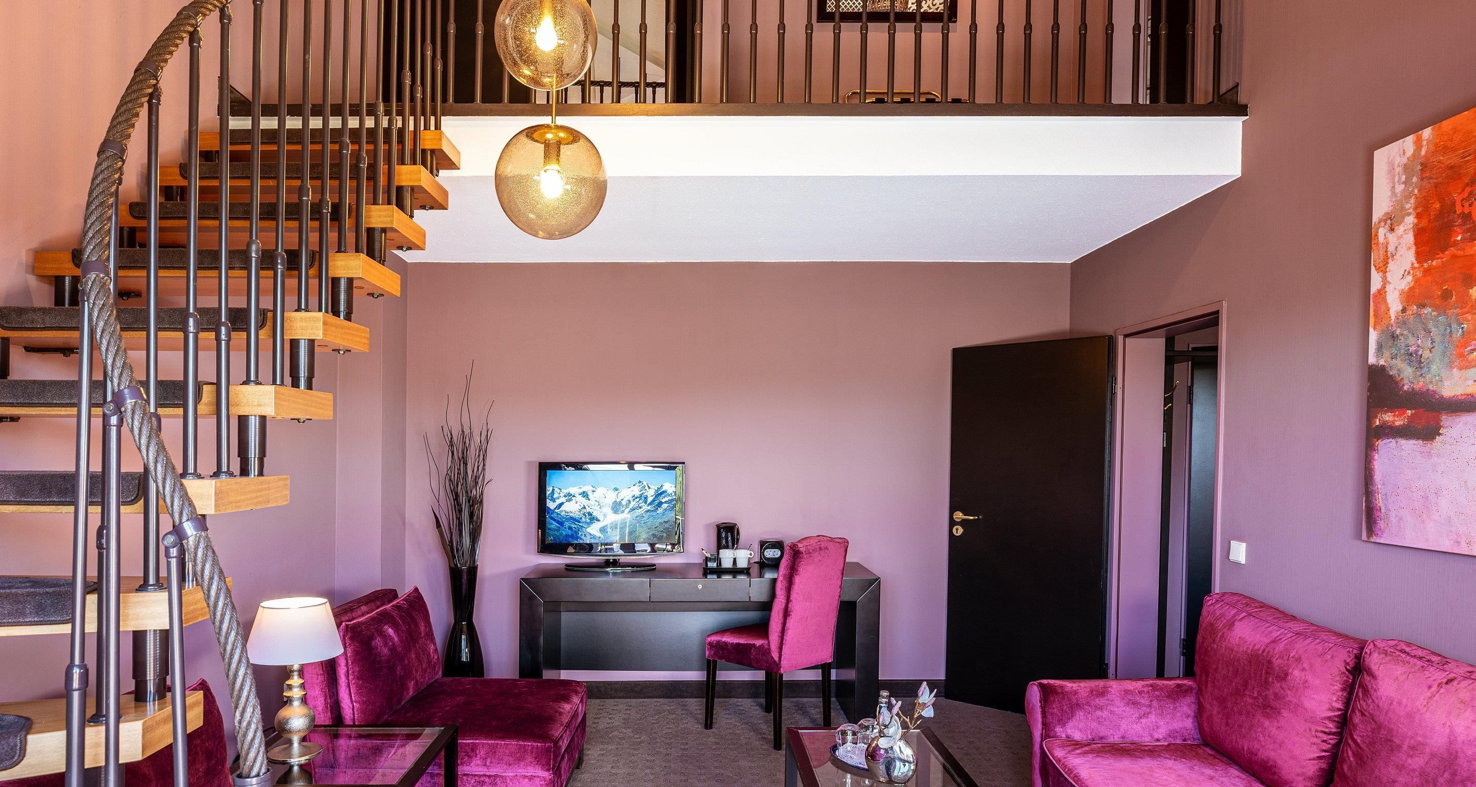 Una sala de estar moderna con una escalera, un televisor de pantalla plana, un escritorio y una puerta.
