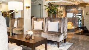 A modern lobby with a grey upholstered sofa, a wooden coffee table, and a large potted plant. - Best Western Victor's Residenz-Hotel Rodenhof (Saarbrücken)