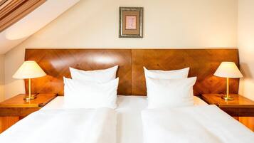 Una camera d'albergo con una testiera in legno, due lampade sui comodini e un quadro appeso al muro.