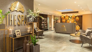Eine moderne Spa-Lobby mit einer Rezeption, einer Sitzecke und dekorativen Pflanzen.