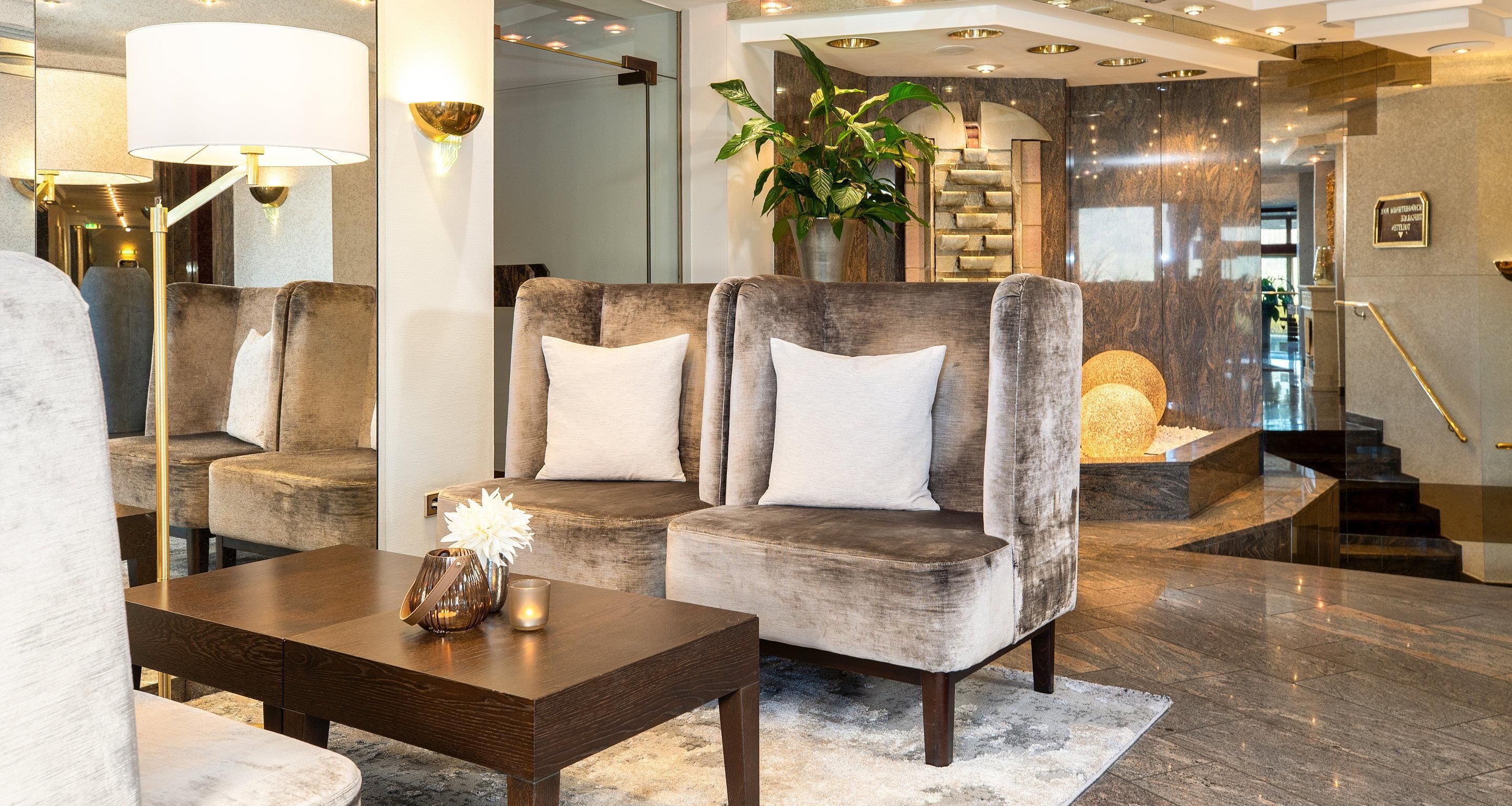 Eine moderne Lobby mit einem grau gepolsterten Sofa, einem Holztisch und einer großen Topfpflanze.