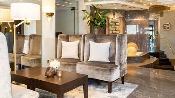 Eine moderne Lobby mit einem grau gepolsterten Sofa, einem Holztisch und einer großen Topfpflanze.