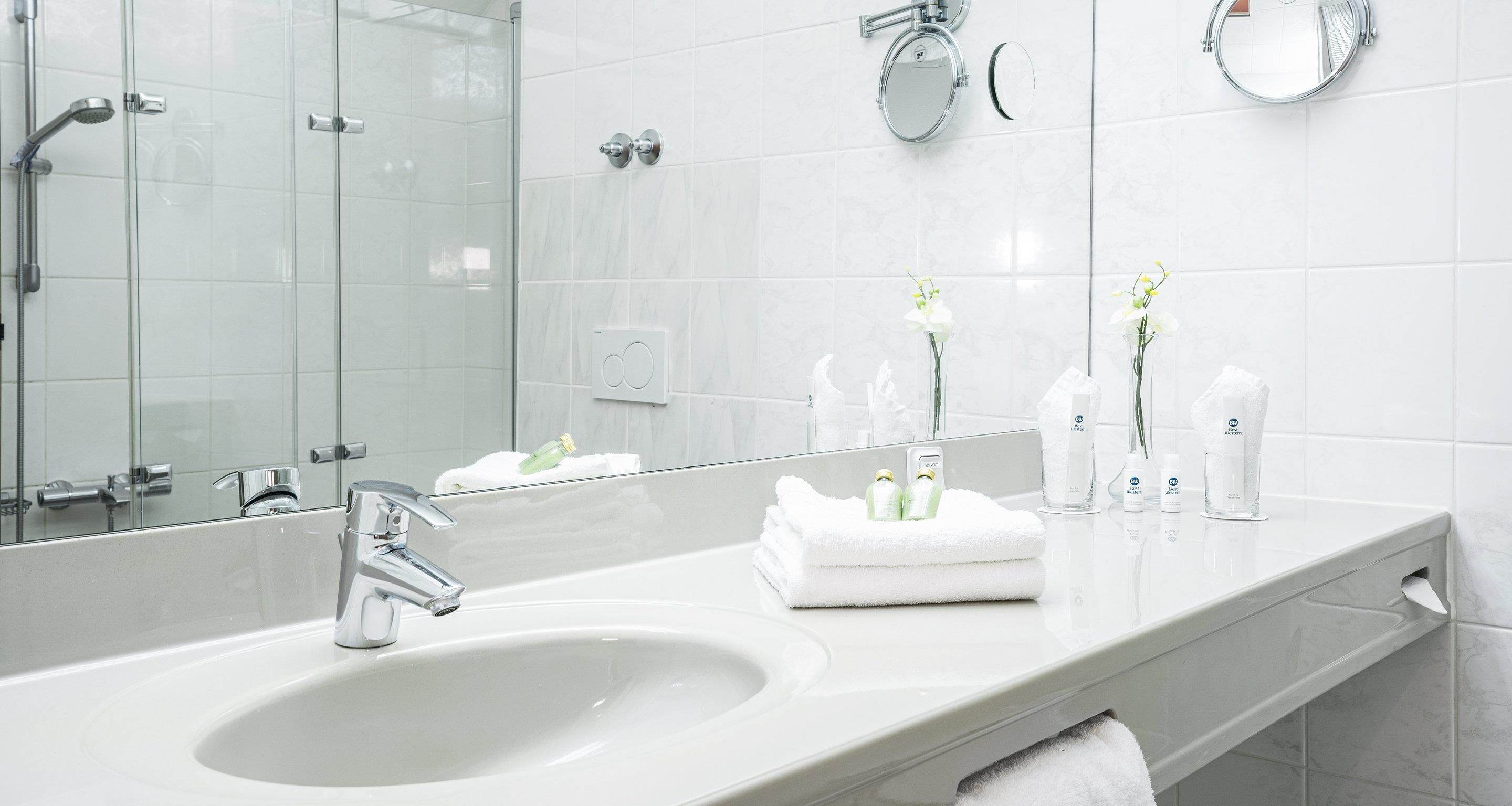 Une salle de bain moderne avec un grand miroir, un lavabo et une douche à parois de verre.