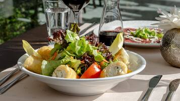 Ein Tisch mit einer Salatschüssel, einer Weinflasche und einem Teller mit Essen.