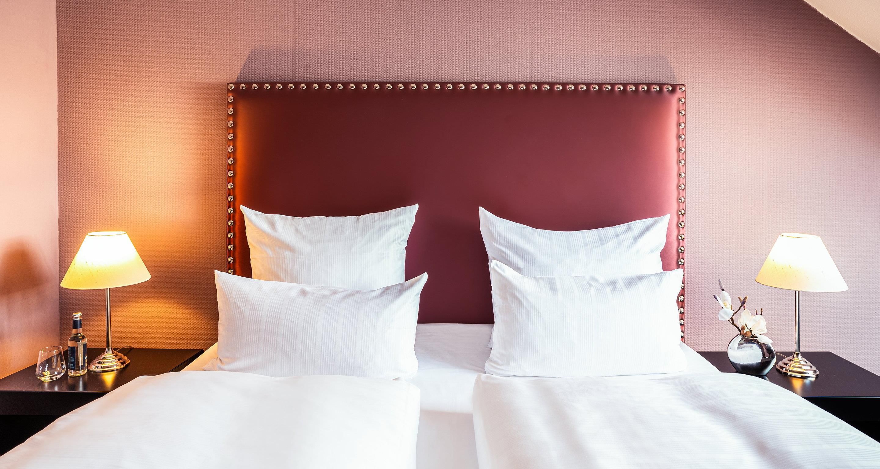 Una habitación de hotel con una cama grande, dos mesitas de noche y lámparas.