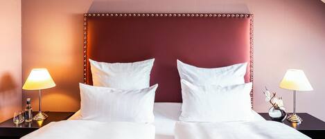 Quarto de hotel com uma cama grande, duas mesas de cabeceira e luminárias.