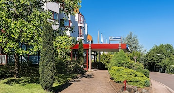 Un hotel con toldo rojo, el letrero de Best Western y un camino pavimentado que conduce a la entrada.