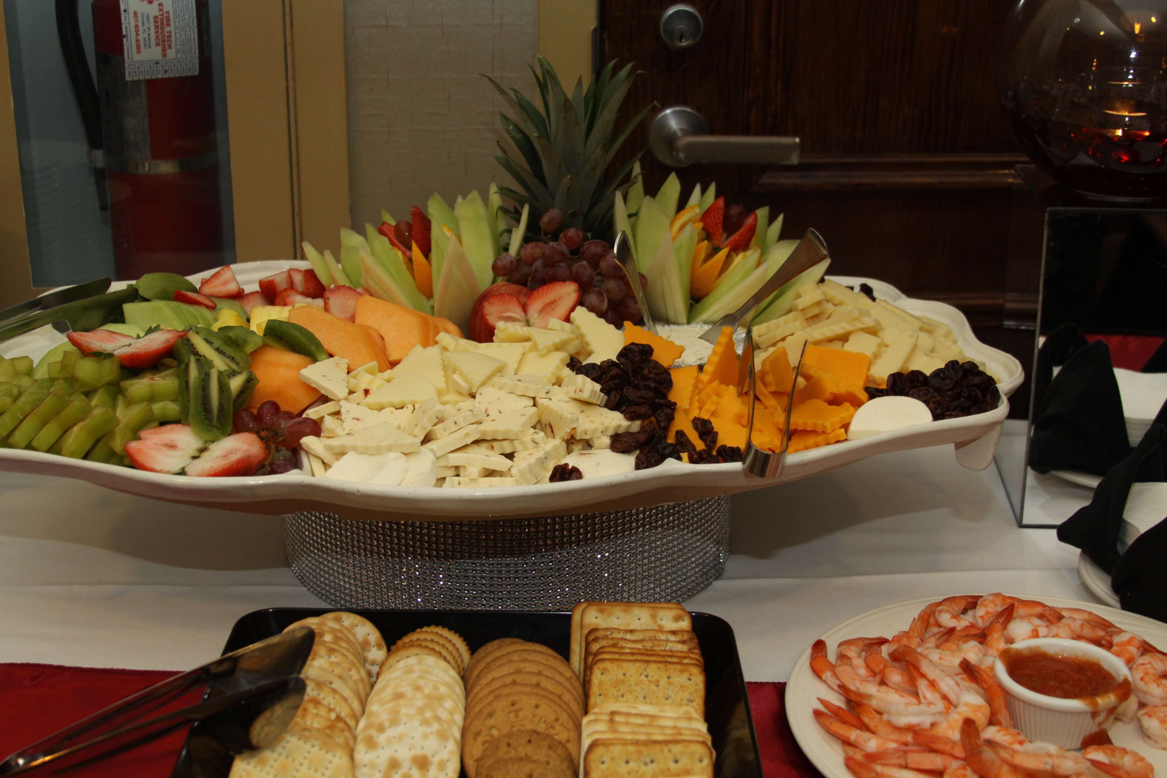 A buffet with a variety of fruits, cheeses, and shrimp.