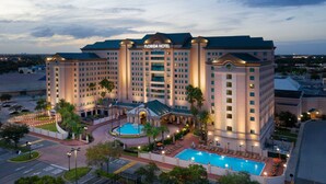 A large hotel with a central courtyard, a swimming pool, and multiple parking spaces. - Florida Hotel & Conference Center in the Florida Mall (Orlando)