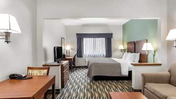 Habitació d'hotel amb un llit, escriptori amb telèfon, cadira, televisió i un sofà.