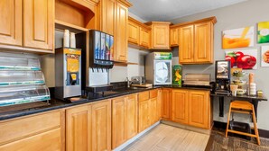Cozinha com armários de madeira, máquina de waffles, geladeira, cafeteira e micro-ondas.