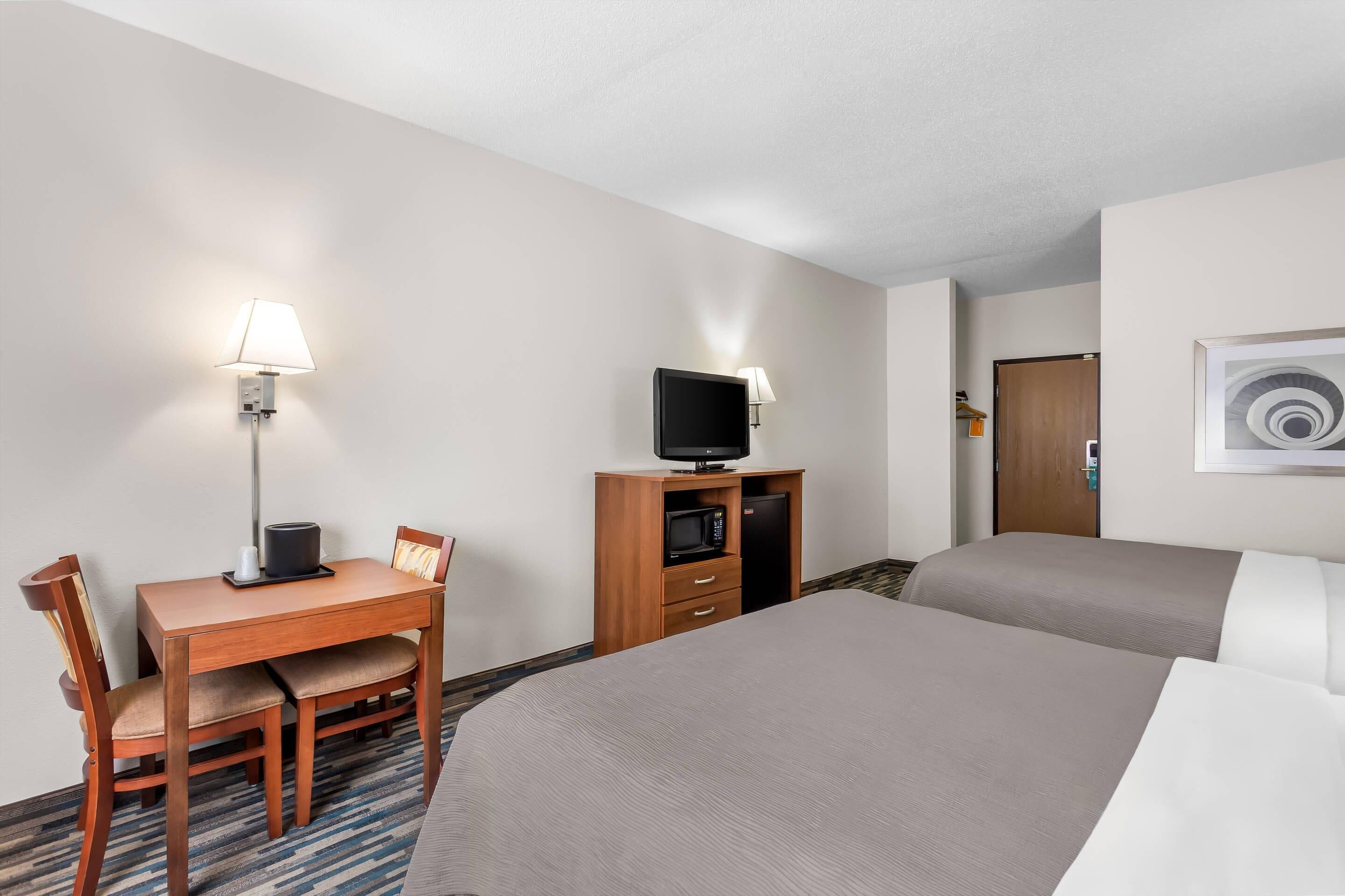 Habitación de hotel con una cama, un escritorio con silla, televisión y microondas.