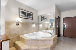 A modern bathroom with a large bathtub, a mirror, and two wall-mounted lamps.