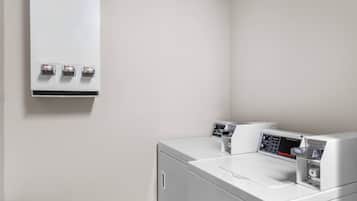 Un área de lavandería con dos lavadoras blancas y una secadora de pared.