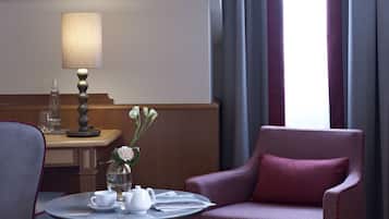 Una habitación de hotel con una mesa redonda, una silla, una lámpara y una ventana con cortinas.