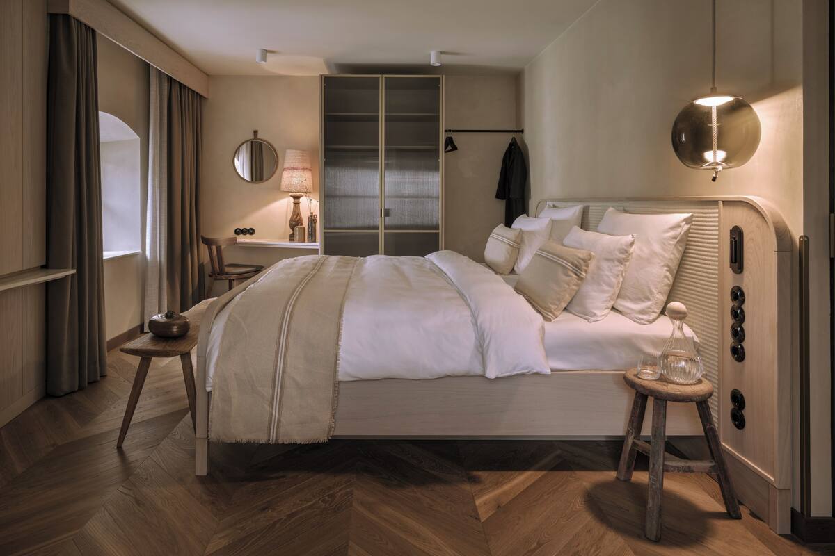 Un dormitorio moderno con una cama grande, una mesita de noche, una lámpara y un armario.