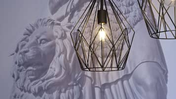 Une statue représentant une tête de lion et revêtue d’un drapé, éclairée par des lampes suspendues aux formes géométriques.