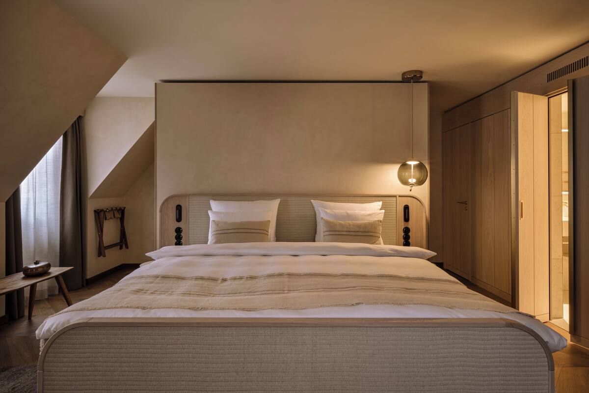 Un dormitorio moderno con una cama grande, una mesita de noche, una lámpara colgante y un armario.