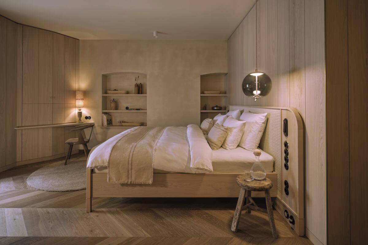 Un dormitorio con cama, mesitas de noche, estantes y una lámpara colgante.