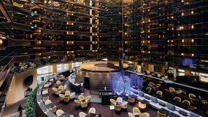Interior de hotel com vários níveis, bar circular central e design moderno.