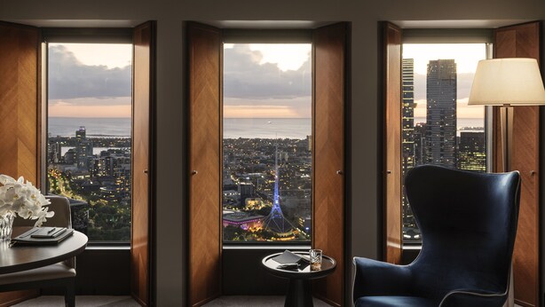 Quarto de hotel com vista para a paisagem urbana, uma mesa com um vaso de flores e uma cadeira.