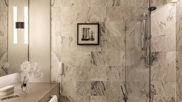 A modern bathroom with marble tiles, a framed picture, a bathtub, and a shower.