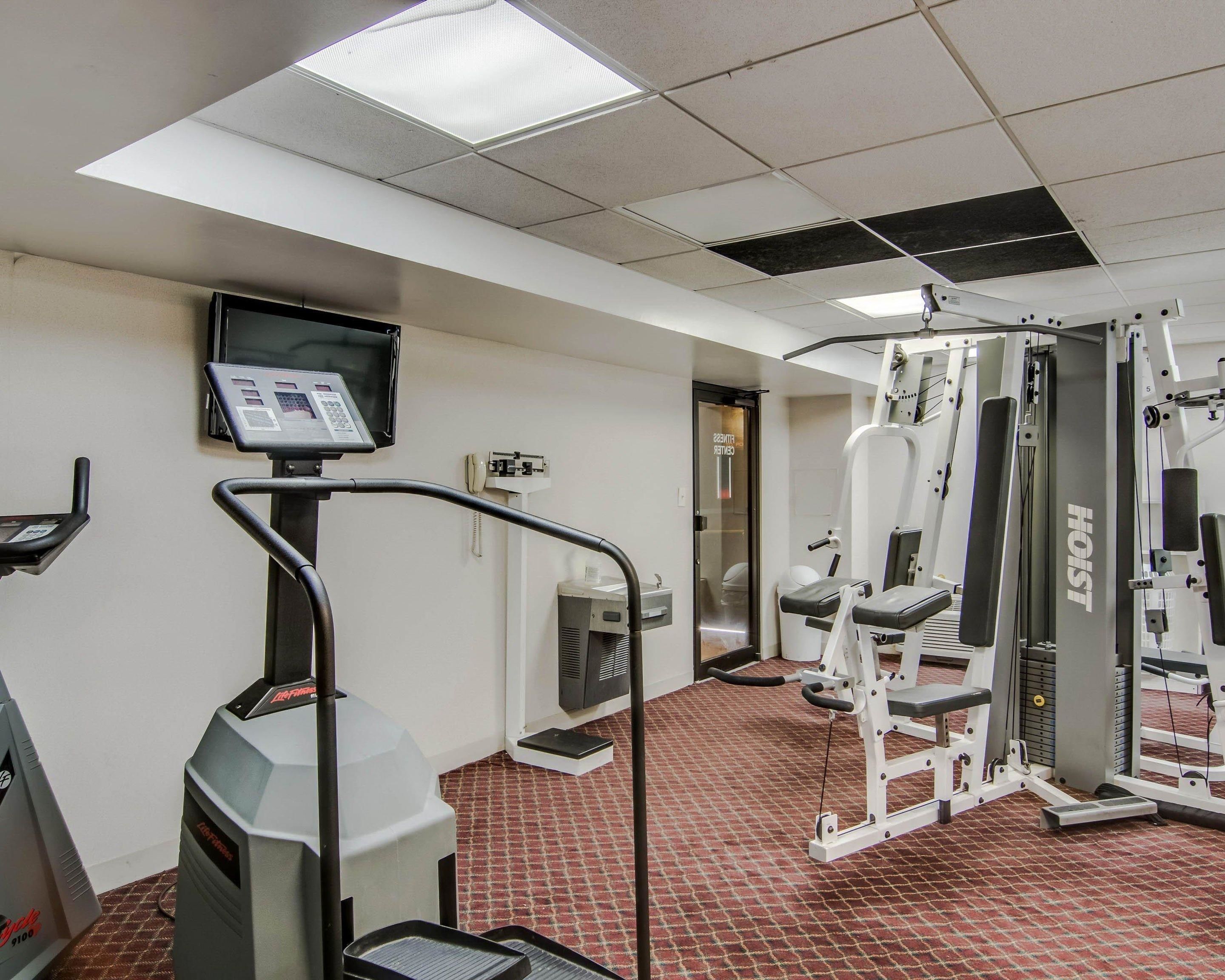 A fitness center with treadmills, weight machines, and a television screen.