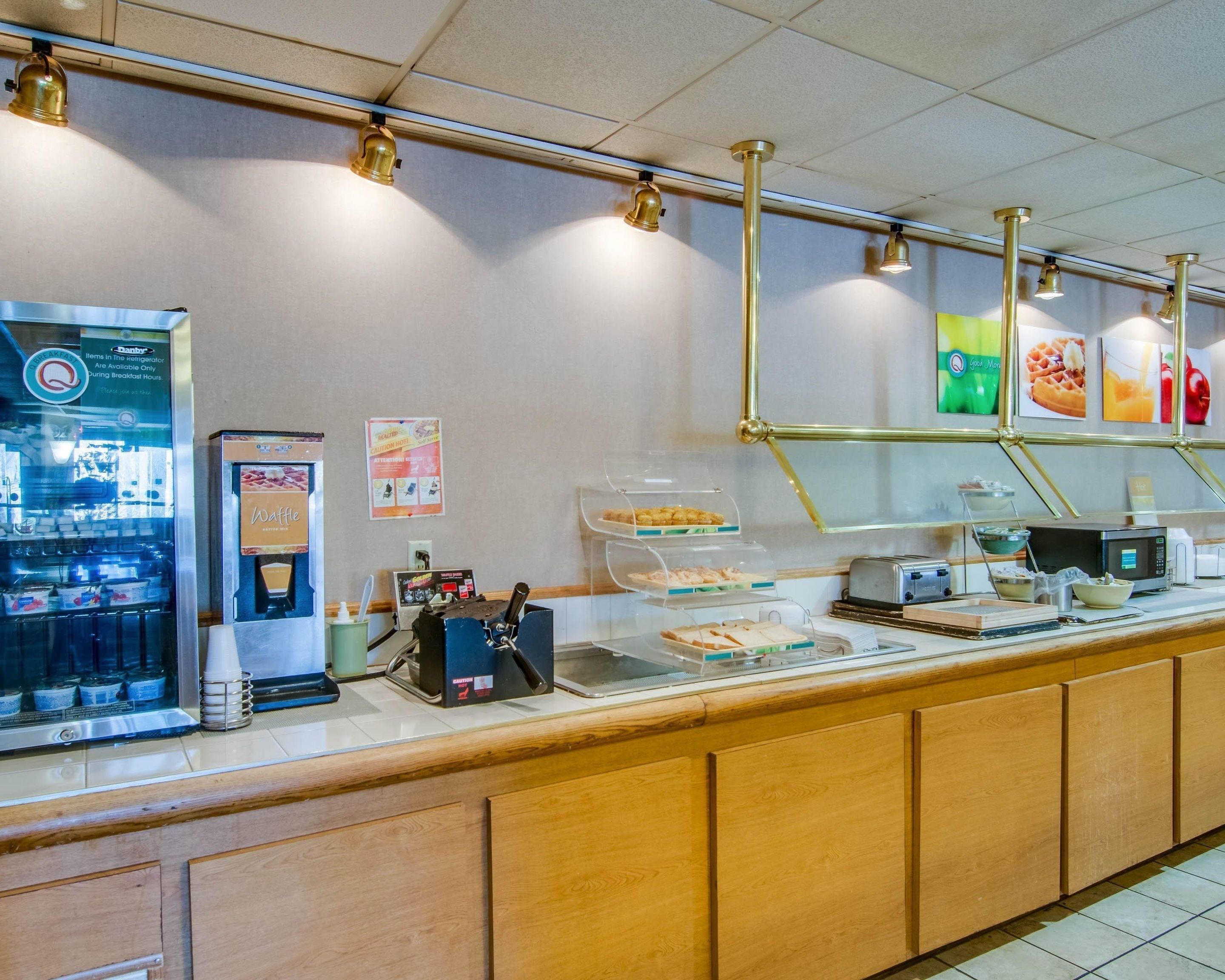 Zona de desayuno autoservicio con máquina de café, estación de gofres y diferentes mostradores de alimentos.