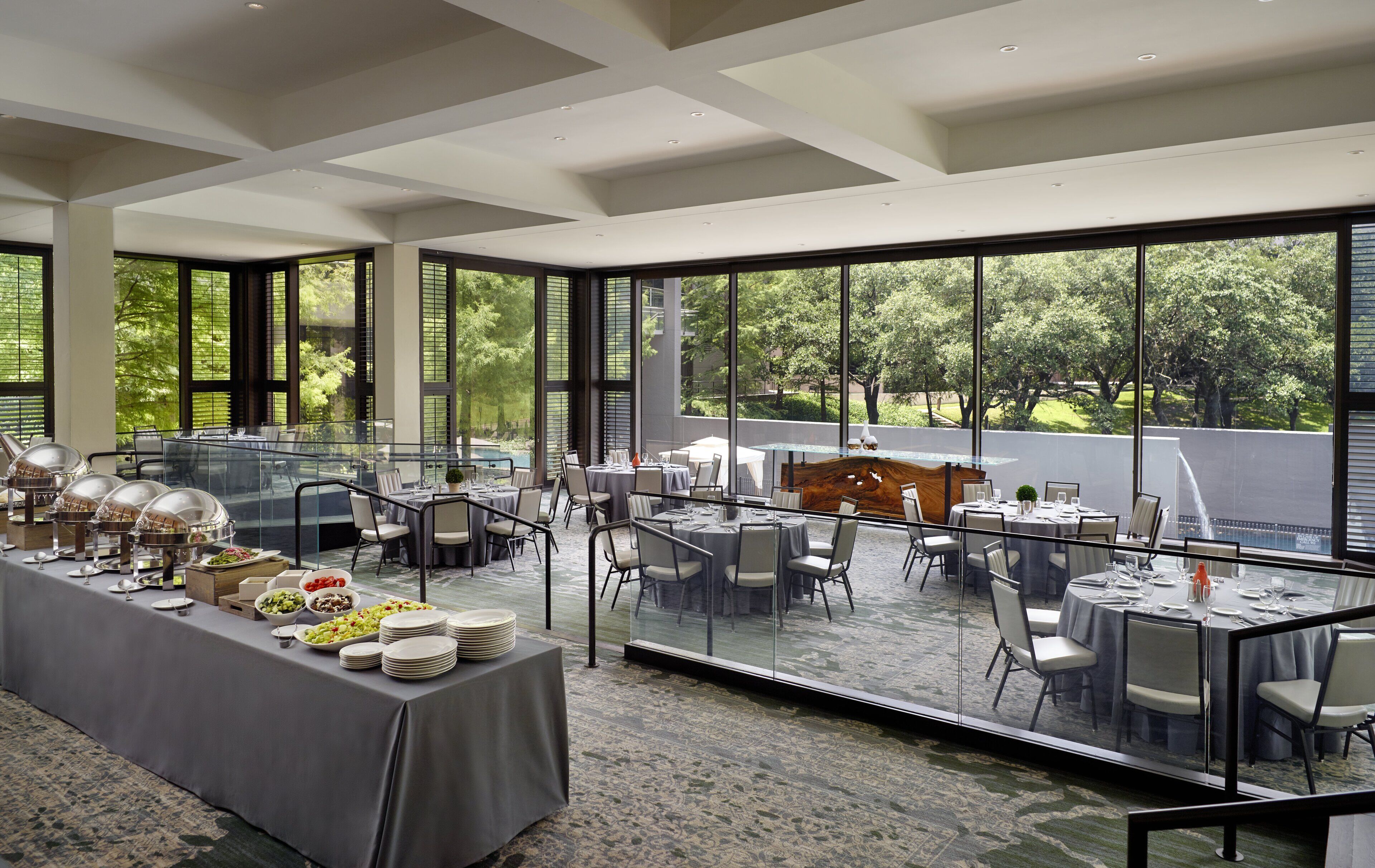 Ein geräumiger Essbereich mit Buffet, großen Fenstern mit Blick ins Freie und einem modernen architektonischen Deckenstil.