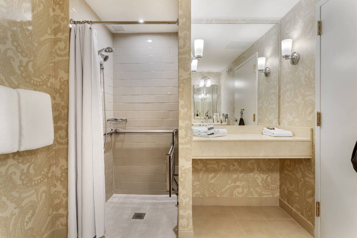 A modern bathroom with a walk-in shower, a vanity with a mirror, and a towel rack.