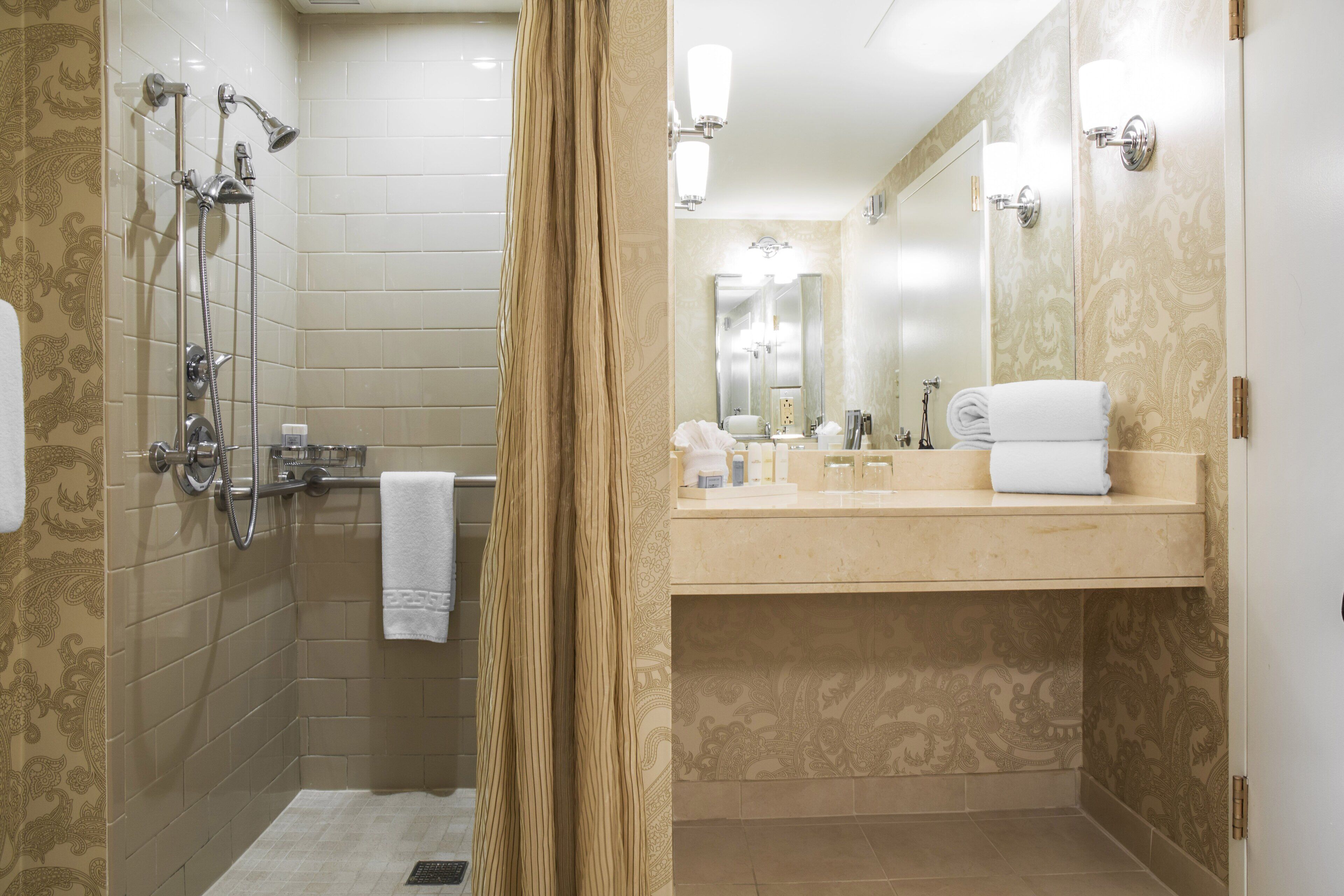Un baño con ducha, lavamanos y espejo.