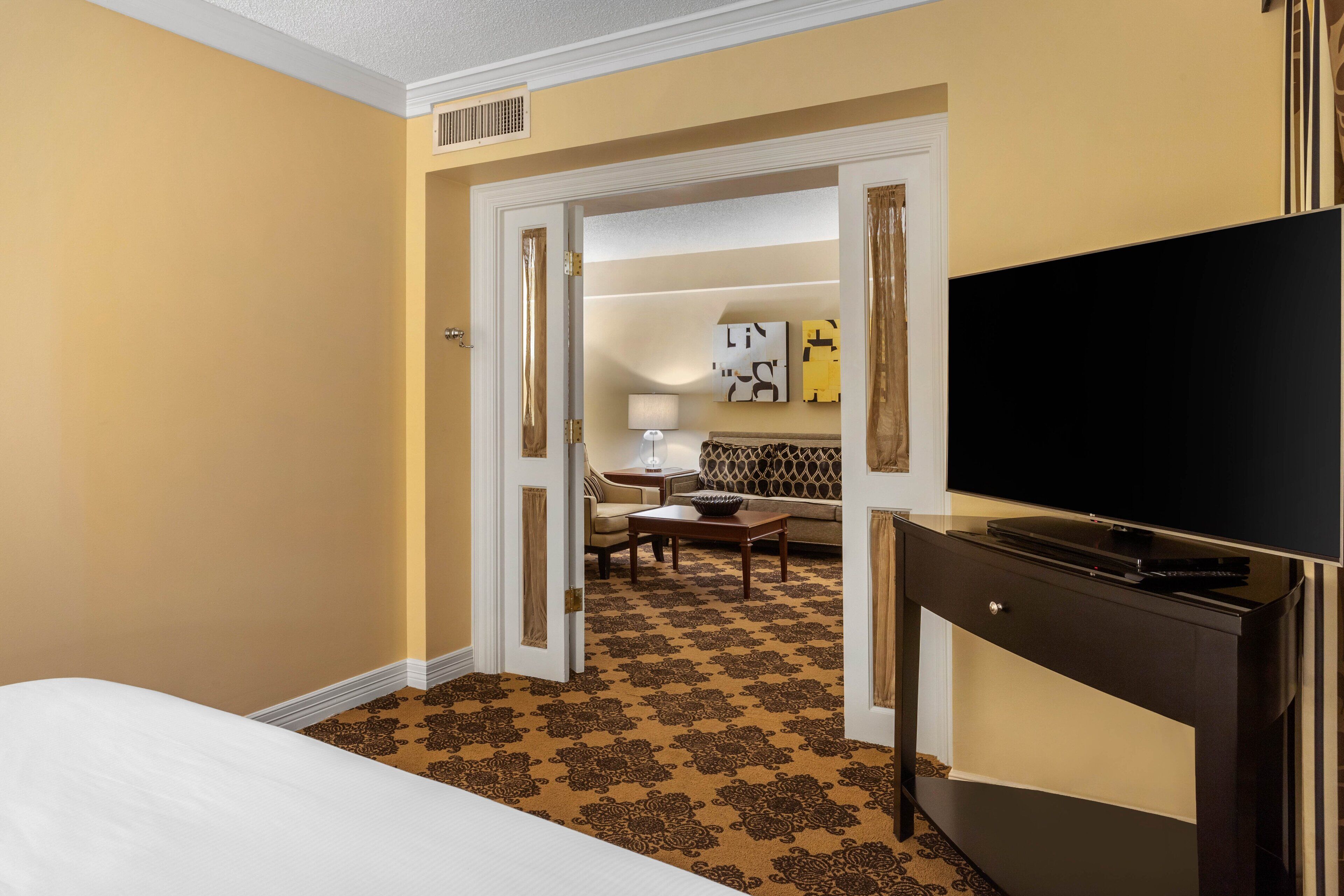 A hotel room with a bed, a TV, a desk, and a sofa.