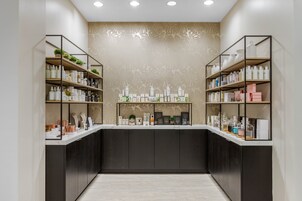 A modern reception area with a central counter, flanked by two shelving units filled with various products.