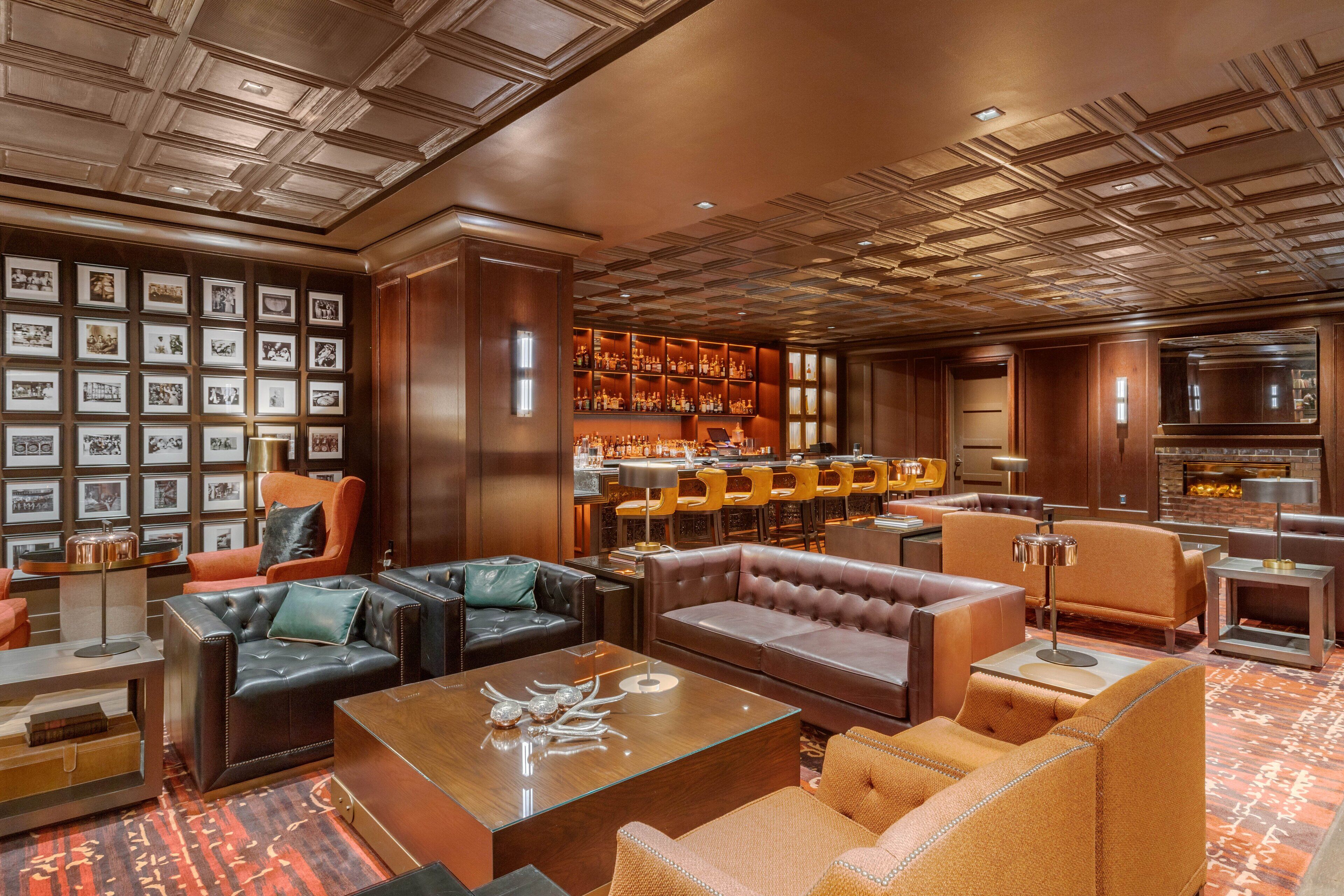 A luxurious lobby with leather sofas, a bar area, and a wall of framed photographs.